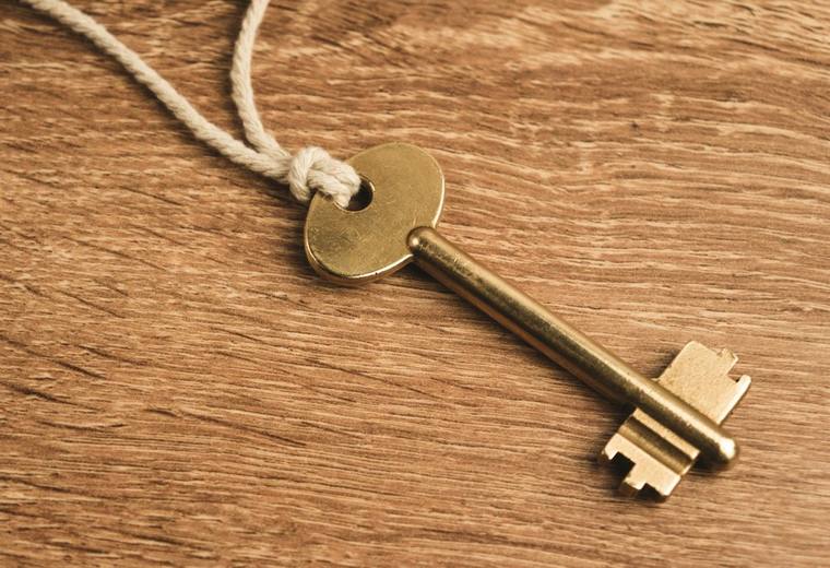 Une clé dorée attachée à une cordelette, posée sur du bois